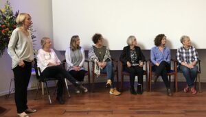 Six women sitting and one woman standing