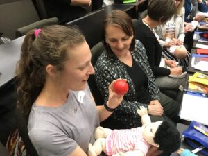 Two woman holding a baby doll and a ball