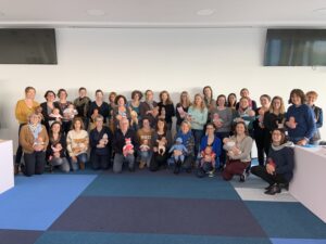 Approximately twenty men and women holding baby dolls