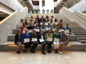 Approximately twenty women sitting on the stairs in four rows