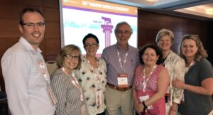 Two men and five women in front of a powerpoint presentation