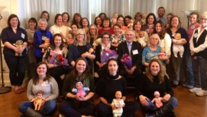 Approximately twenty men and women holding baby dolls